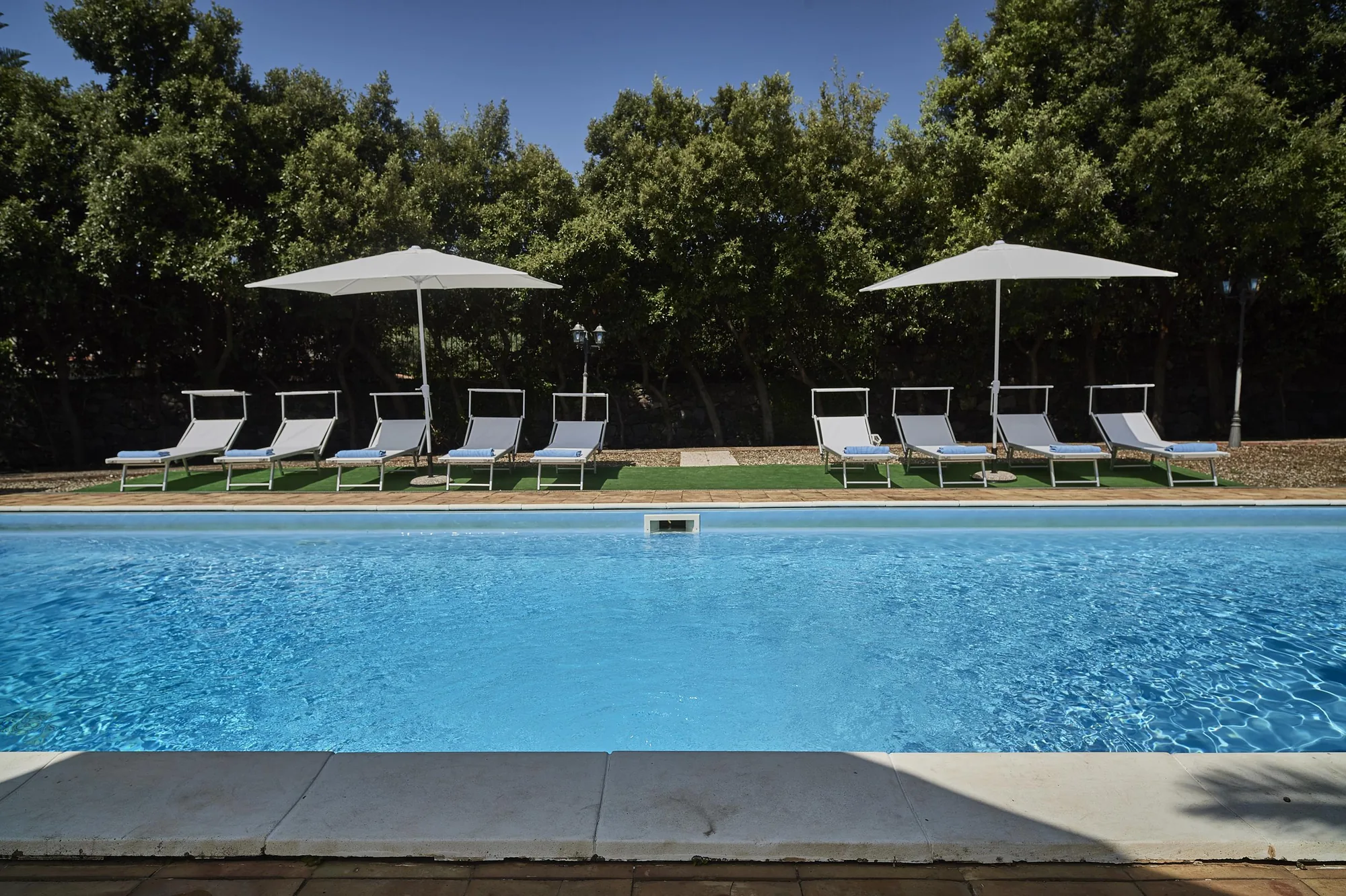 Der private Pool mit Liegen und Sonnenschirmen